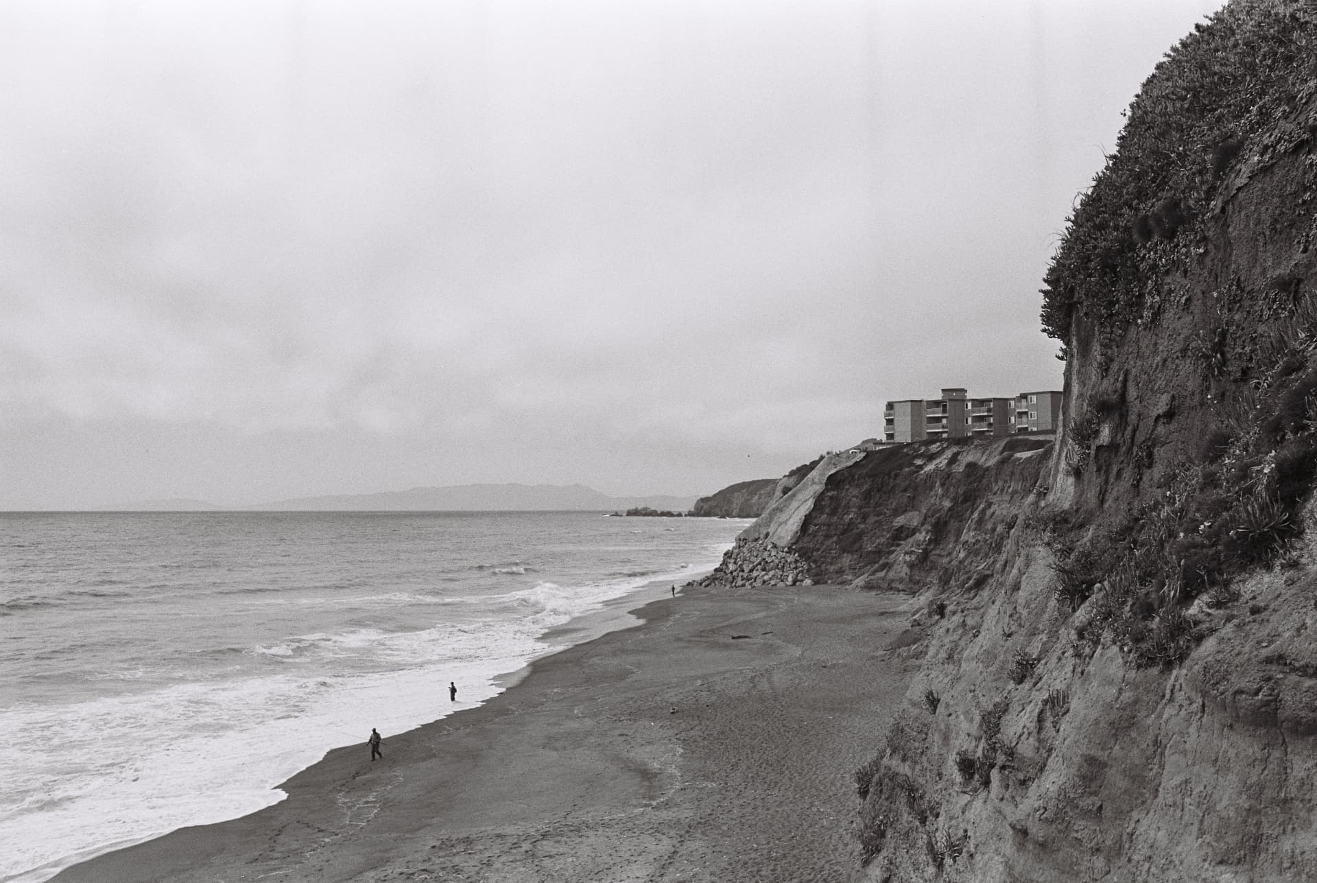 Black-and-white coastal cliffs and buildings above the ocean
