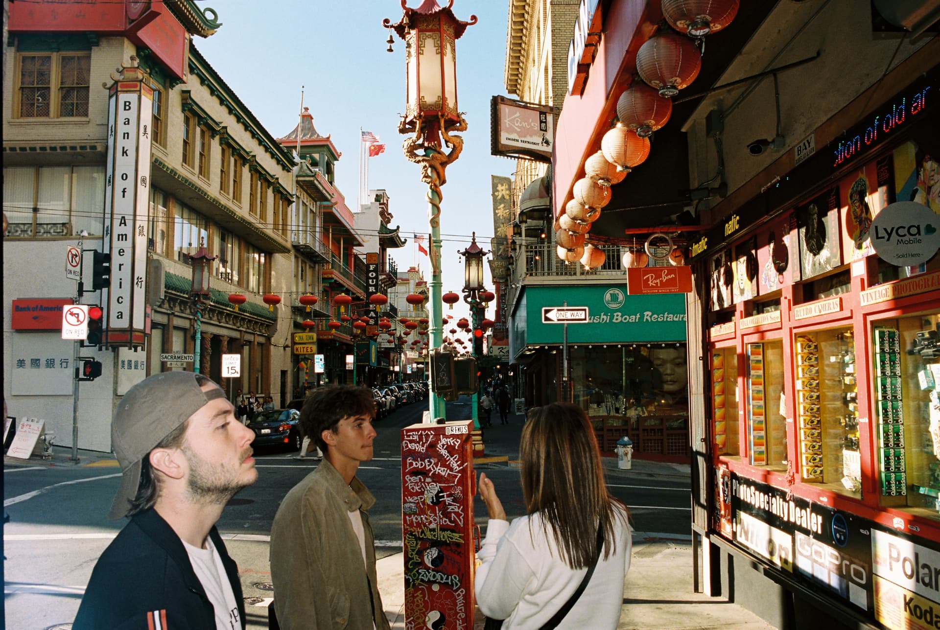 People walking beneath red lanterns on a Chinatown street