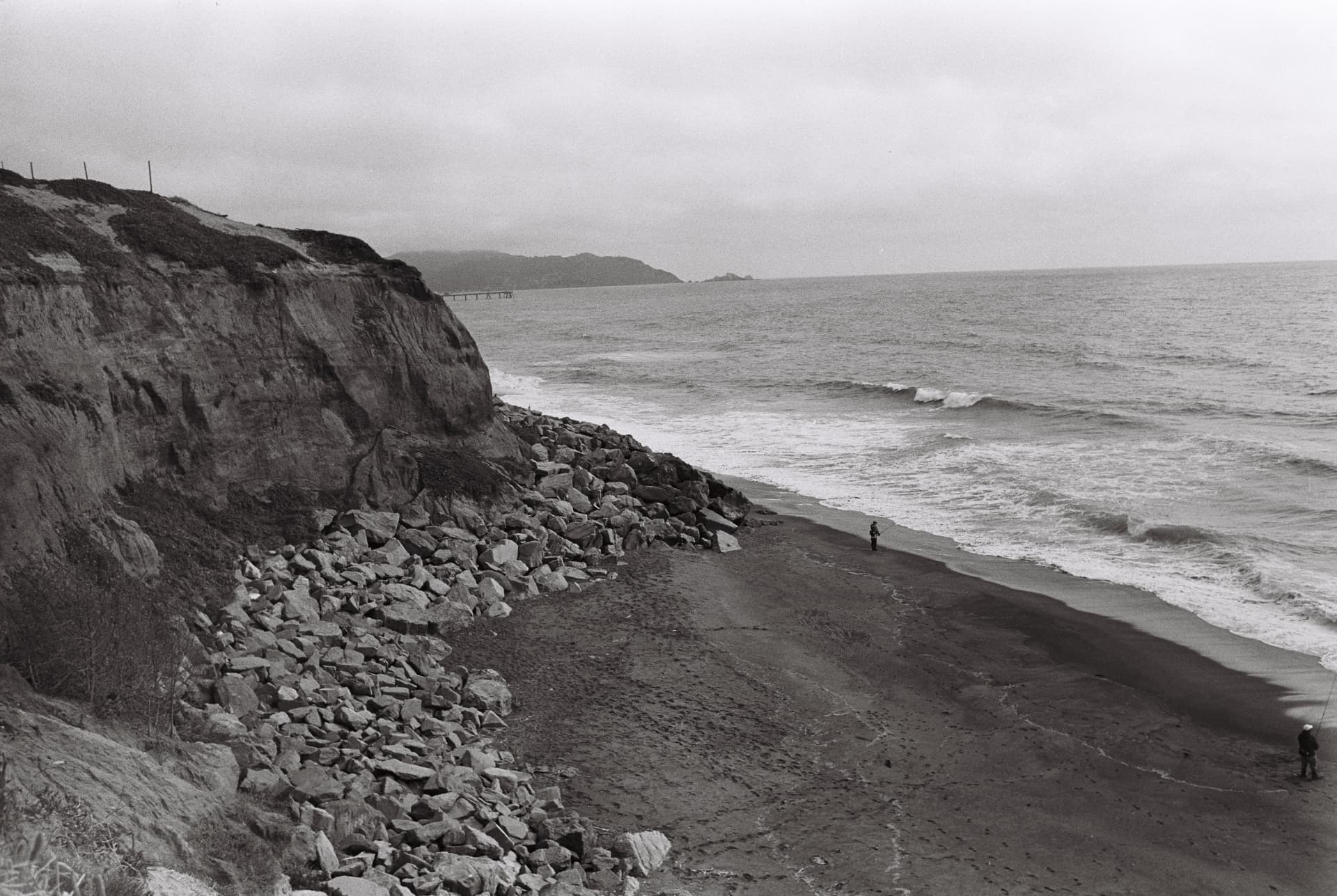 Black-and-white rocky coastline and waves along a beach