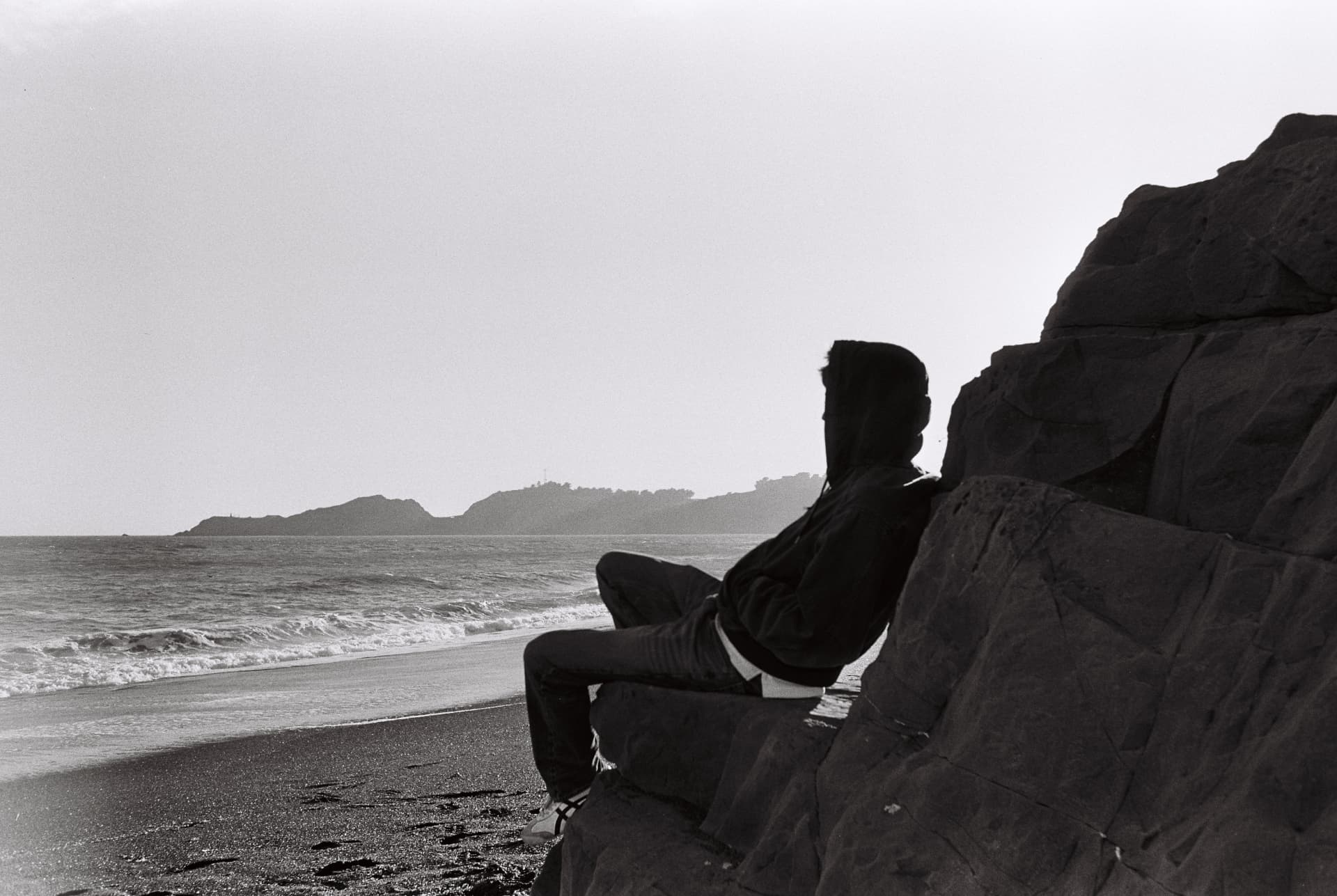 Black-and-white portrait of a person seated on coastal rocks