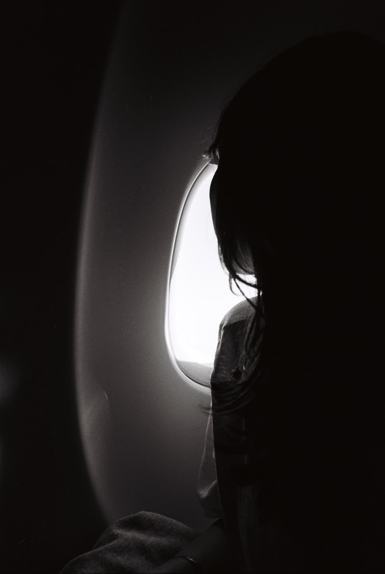 Silhouette of a passenger beside an airplane window