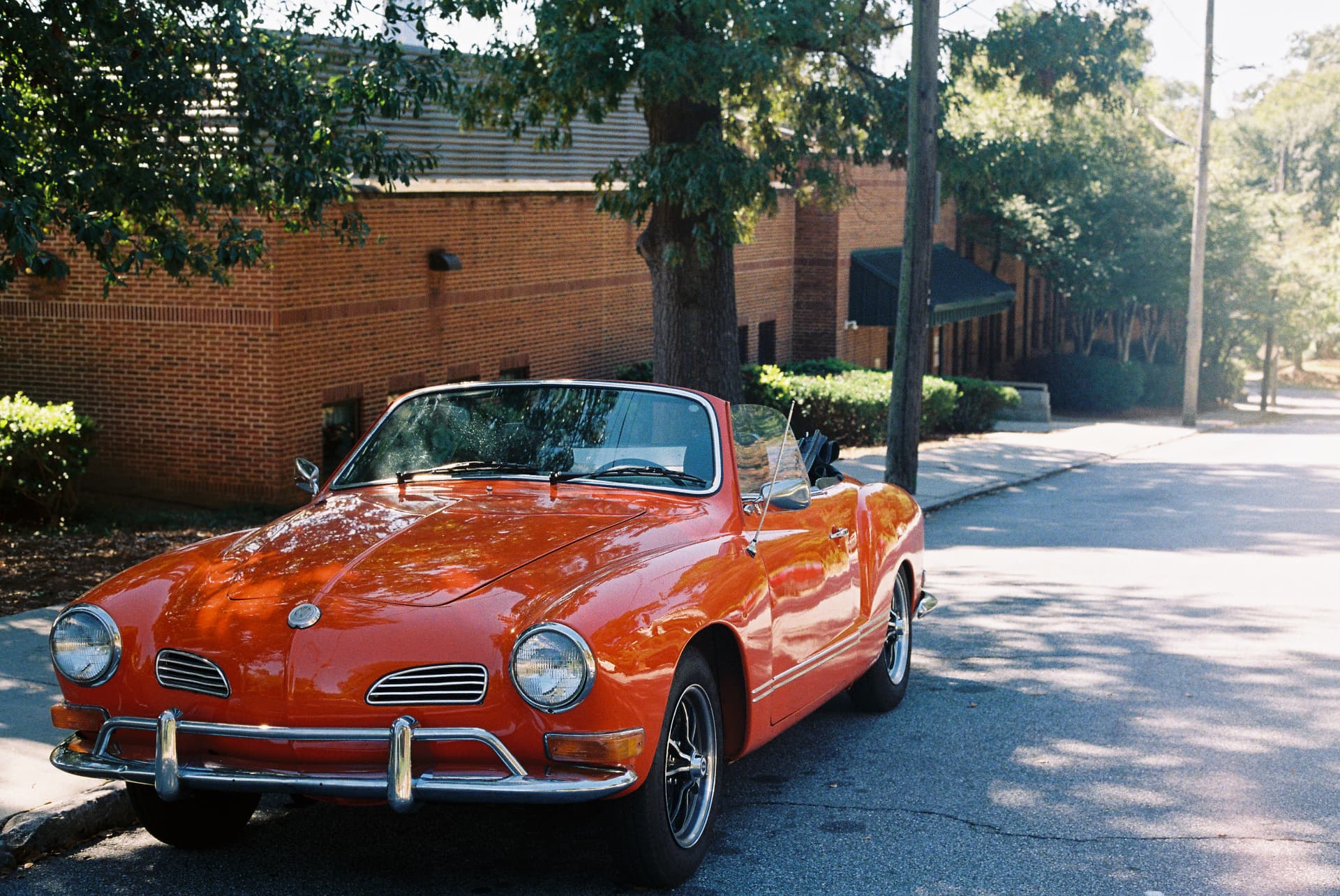 Red vintage convertible parked on a tree-lined street