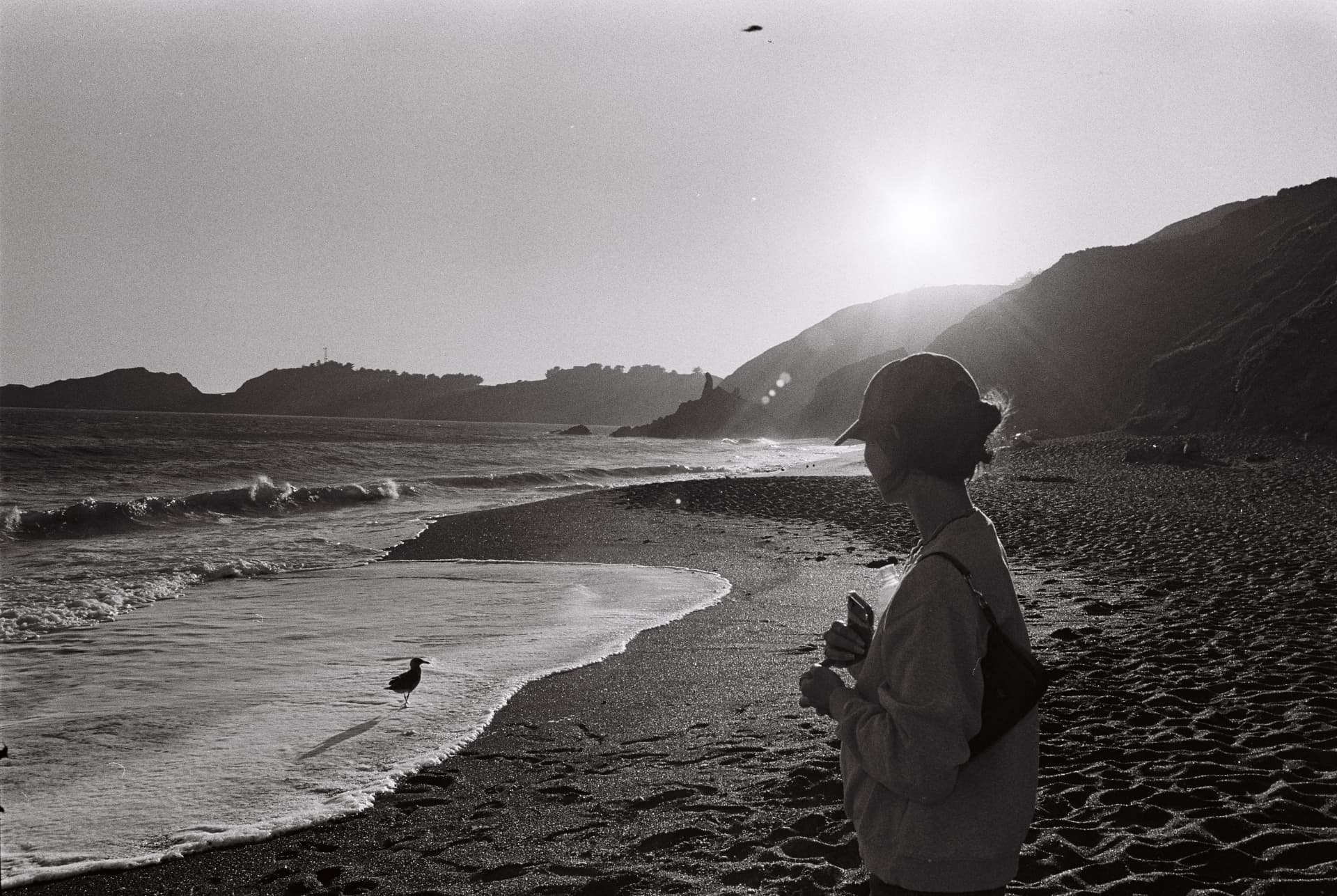 Black-and-white portrait beside a rocky coast at sunset