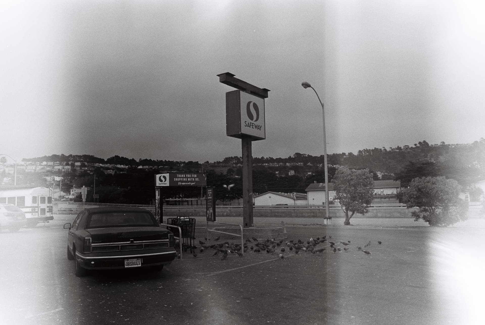Black-and-white street scene with a car and roadside signs